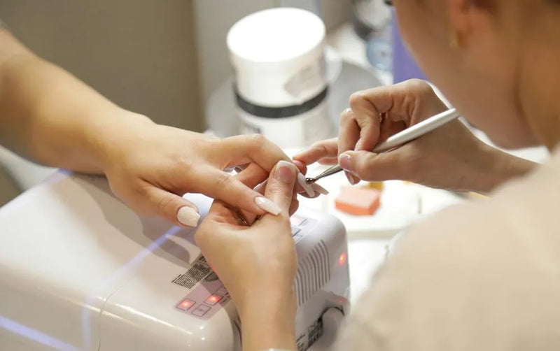 Estetista applica lo smalto semipermanente durante un trattamento compreso in un pacchetto